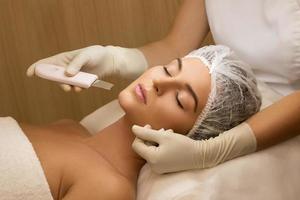 mulher no salão de spa de beleza profissional durante o procedimento de limpeza facial ultra-sônica foto