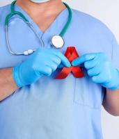 médico de uniforme azul e luvas de látex estéreis segura uma fita vermelha foto