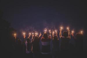 grupo de jovens amigos se divertem com fogos de artifício nas mãos juntos foto