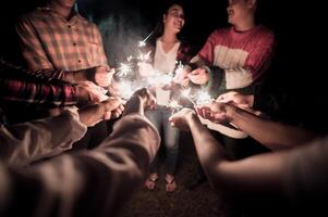 fogos de artifício queimando estrelinha em mãos humanas na noite de festa de ano novo foto