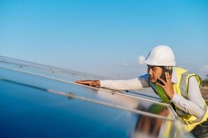 jovem engenheiro usa smartphone enquanto trabalha na fazenda solar foto