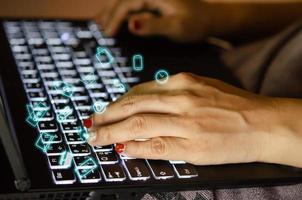 mãos usando um teclado com sobreposição de ícones digitais foto