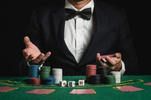 foto de corte de close-up homem dealer ou croupier embaralha cartas de pôquer apostando no cassino em fundo preto de mesa verde, negociante homem convite apostar cartas de baralho. cassino, pôquer, conceito de jogo de pôquer