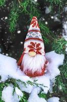 cartão de férias de natal gnomos escandinavos fofos com chapéu vermelho e barba branca no banco de inverno nevado conto de fadas queda de neve inverno olá dezembro, janeiro, conceito de fevereiro feliz ano novo, natal foto