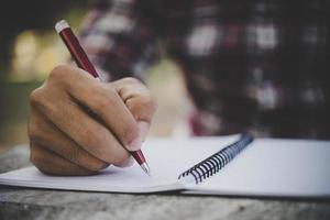 homem escrevendo a mão em seu caderno foto