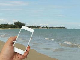 pessoa segurando telefone na praia foto