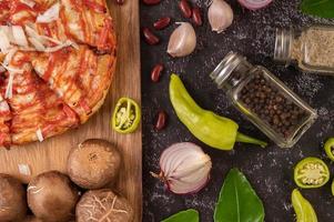 pizza em uma placa de madeira com pimentão, alho, pimenta e cogumelos shiitake foto