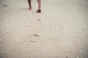 jovem em pé na praia com os pés descalços foto