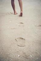 jovem em pé na praia com os pés descalços foto