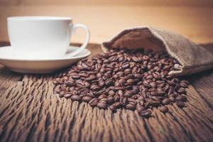 xícara de café com grãos de café em uma mesa de madeira