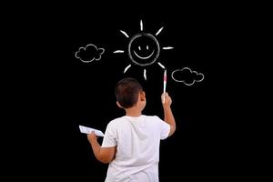 um menino desenha o céu e o sol em um quadro-negro