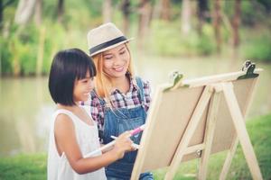 mãe e filhas fazendo desenhos juntas em um parque foto