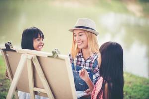 mãe e filhas fazendo desenhos juntas em um parque foto