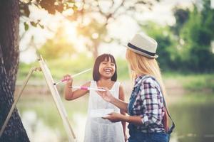 mãe e filhas fazendo desenhos juntas em um parque foto