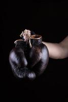 a mão do homem segura um par de luvas de boxe marrons de couro velho foto