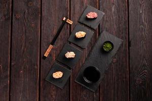 conjunto de sushi gunkan maki com diferentes tipos de peixe salmão, vieira, poleiro, enguia, camarão e caviar no fundo da mesa de madeira. cardápio de sushi. vista superior do conjunto de sushi de comida japonesa gunkans foto