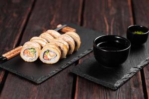 rolo com sushi de peixe com pauzinhos - conceito de comida asiática foto