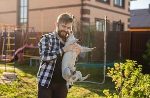 jovem segurando cachorro jack russell terrier perto de sua casa no quintal - dono do animal e animal foto