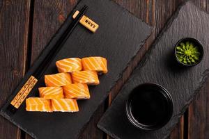 sushi roll philadelphia com salmão e pepino e cream cheese em fundo preto. cardápio de sushi. vista superior do conceito de comida japonesa foto