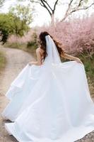 uma jovem noiva em um vestido branco está girando em um caminho foto