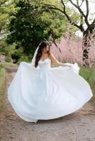 uma jovem noiva em um vestido branco está girando em um caminho foto