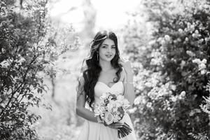 noiva jovem em um vestido branco em uma floresta de primavera em arbustos lilás foto