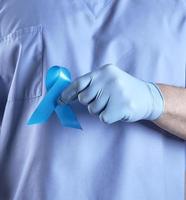 médico de uniforme e luvas de látex segurando uma fita azul na mão foto