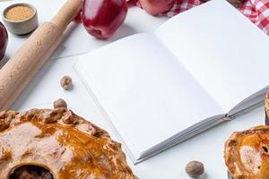maquete de livro de culinária aberta em branco com torta de maçã, torta de carne e frutas da estação foto