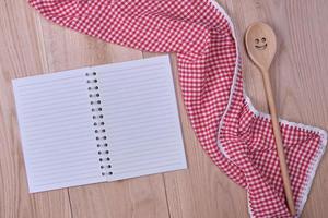 caderno aberto em branco e acessórios de cozinha de madeira foto