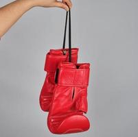 par de luvas de boxe de couro vermelho penduradas em uma corda foto