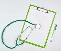 lençóis brancos vazios e estetoscópio médico verde sobre um fundo branco foto