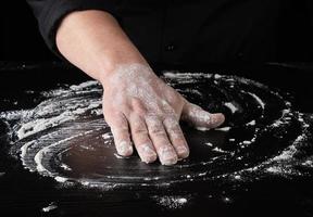 farinha de trigo branca em uma mesa de madeira preta foto