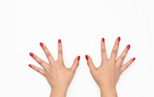 duas mãos femininas com manicure vermelha levantadas sobre um fundo branco foto