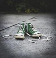 Tênis clássico verde infantil antigo têxtil com cadarço desamarrado foto