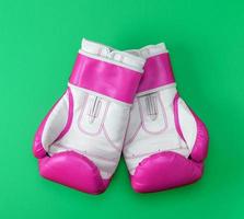 par de luvas de boxe de couro rosa-branco em um fundo verde foto