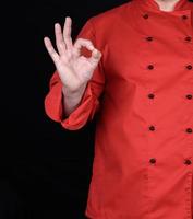 chef de uniforme vermelho mostra um gesto de aprovação com a mão direita foto