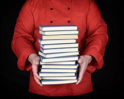 homem de uniforme vermelho segura uma pilha de livros foto