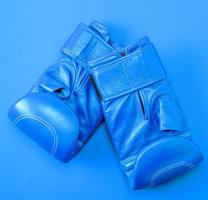 luvas de boxe de couro esporte azul sobre um fundo vermelho foto