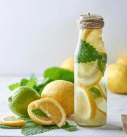 bebida refrescante limonada com limões, folhas de hortelã, limão em uma garrafa de vidro foto