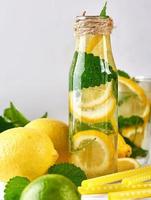 bebida refrescante de verão limonada com limões, folhas de hortelã, limão em uma garrafa de vidro foto