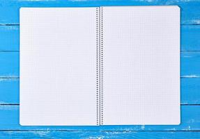 caderno aberto em uma célula em um fundo azul de madeira foto