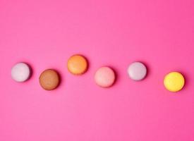 farinha de amêndoa de macarons cozidos coloridos em um fundo rosa foto