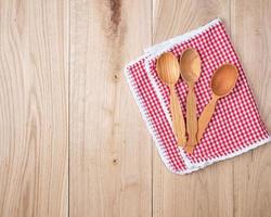 três colheres de pau vazias em uma toalha de cozinha vermelha foto