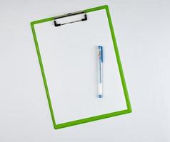 prancheta de papel e caneta azul sobre um fundo branco foto
