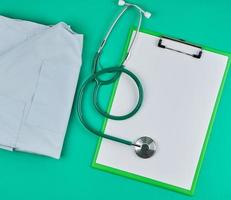lençóis brancos vazios e um estetoscópio médico sobre um fundo verde foto