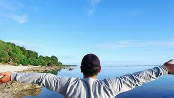 costas do homem usando um chapéu que está olhando para as praias azuis, ilhas e lindo céu azul foto