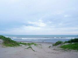 água turquesa, ondas brancas, céu azul, grama verde, areia branca, bela praia e bela ilha, sayang heulang garut, vista panorâmica foto