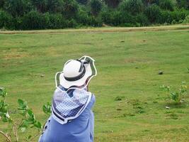 costas da mulher de chapéu que estava sentada olhando para a bela colina verde montando foto