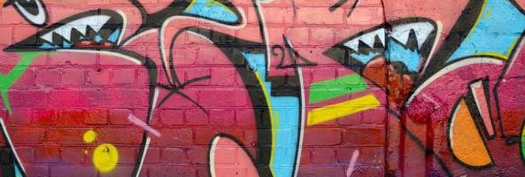 fragmento colorido abstrato de pinturas de grafite na parede de tijolos antigos. composição de arte de rua com partes de letras não escritas e manchas multicoloridas. textura de fundo subcultural foto