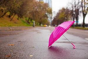 guarda-chuva infantil rosa no asfalto molhado ao ar livre foto